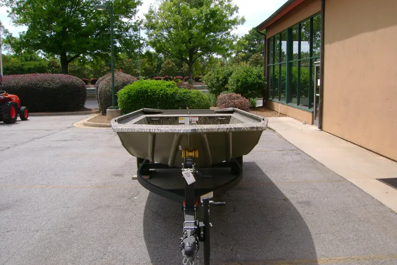 Slide: The Image of 2026 Tracker Grizzly 1754 Utility boat parked outdoors near a building. - 2