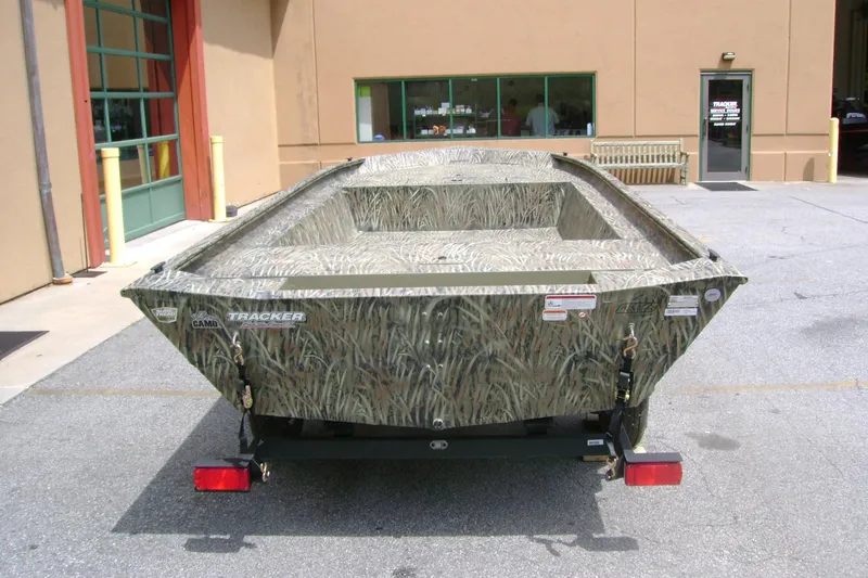 Slide: The Image of 2026 Tracker Grizzly 1754 Utility boat with camouflage design parked outside a building. - 3