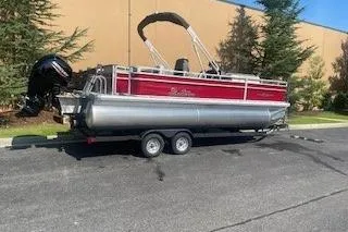 Slide: The Image of 2026 Sun Tracker Fishin' Barge 22 DLX pontoon boat on trailer, parked outdoors. - 1