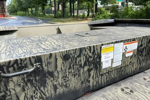 Slide: The Image of 2026 Tracker Grizzly 1754 Utility boat with camouflage pattern and safety labels, parked outdoors. - 7