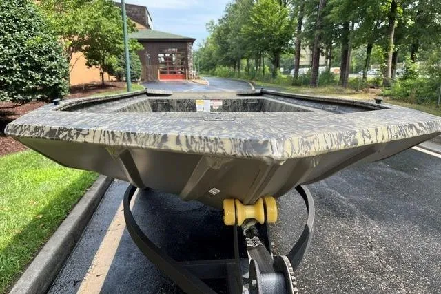 Slide: The Image of 2026 Tracker Grizzly 1754 Utility boat on trailer, parked on a tree-lined road. - 2