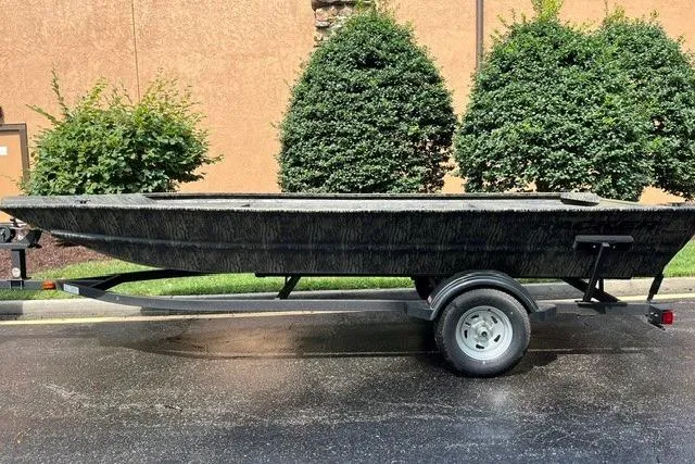 The Image of 2026 Tracker Grizzly 1754 Utility boat on trailer, parked outdoors near greenery. - 0
