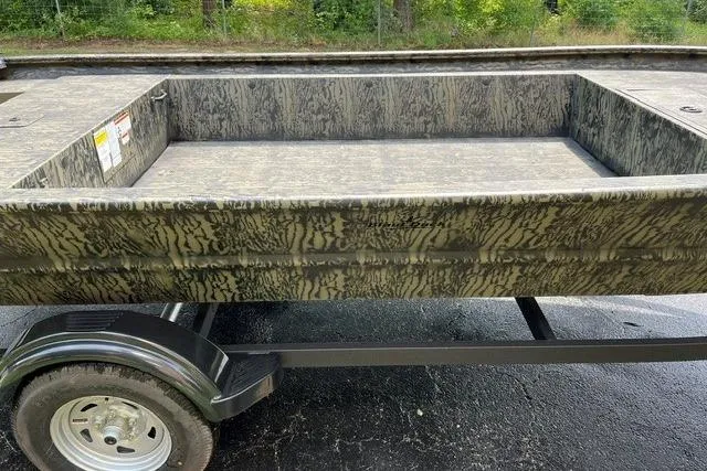 Slide: The Image of 2026 Tracker Grizzly 1754 Utility boat on trailer, camo design, parked outdoors. - 6