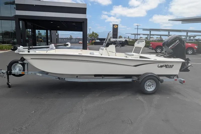 Slide: The Image of 2026 Mako Pro Skiff 17 CC boat on trailer, parked outdoors near dealership. - 2