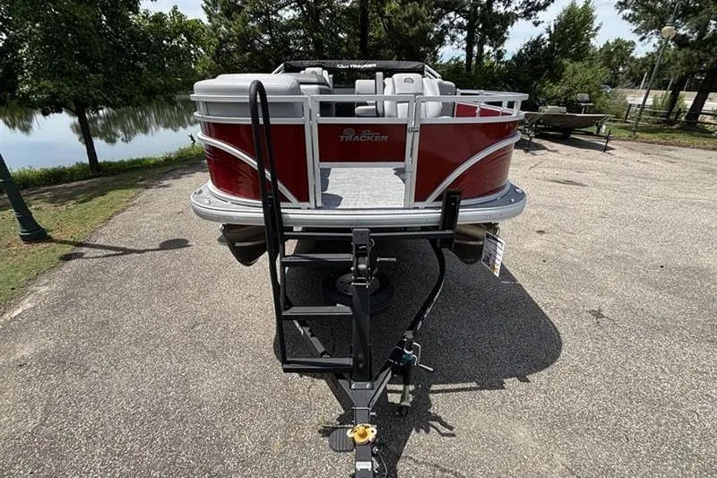 Slide: The Image of 2026 Sun Tracker SportFish 20 DLX pontoon boat on trailer, parked near a lake. - 1
