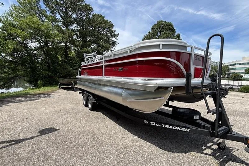 Slide: The Image of 2026 Sun Tracker SportFish 20 DLX pontoon boat on trailer, parked outdoors. - 2