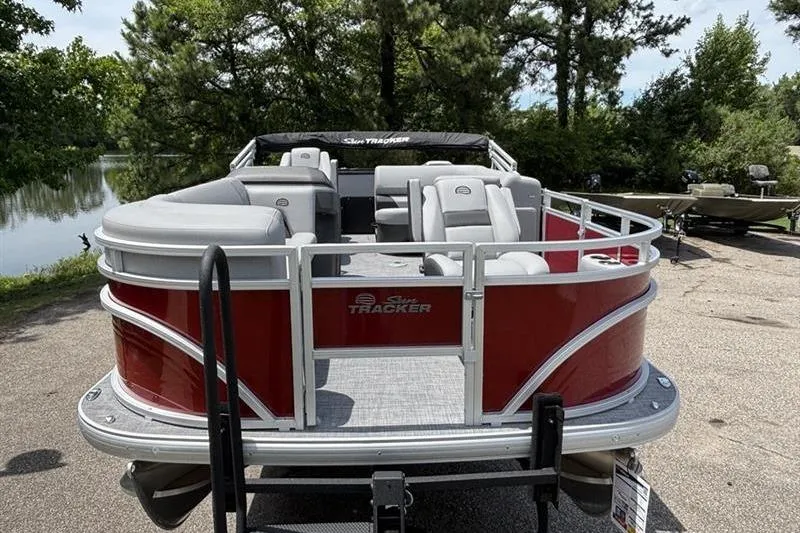 Slide: The Image of 2026 Sun Tracker SportFish 20 DLX pontoon boat with red exterior, parked near a scenic lake. - 4