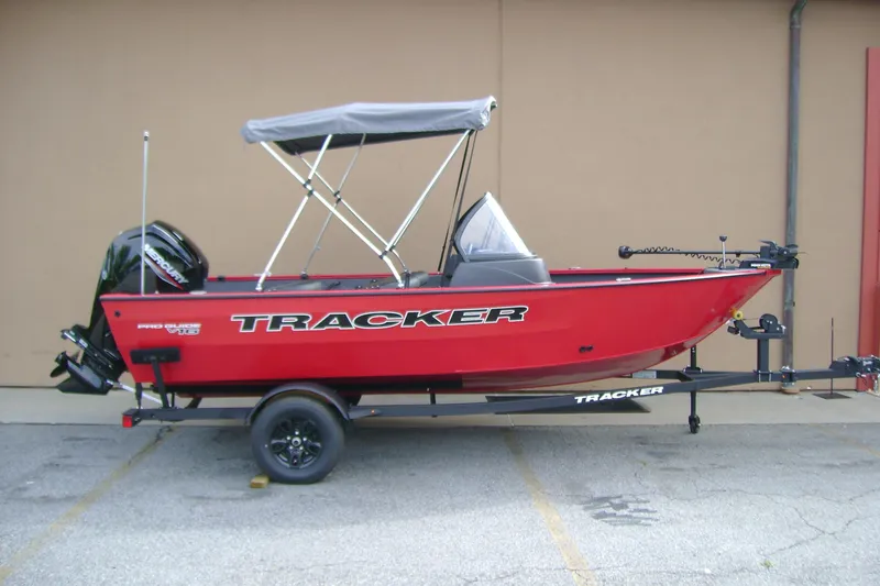 The Image of 2026 Tracker Pro Guide V-16 WT boat, red with canopy, on trailer in parking lot. - 0