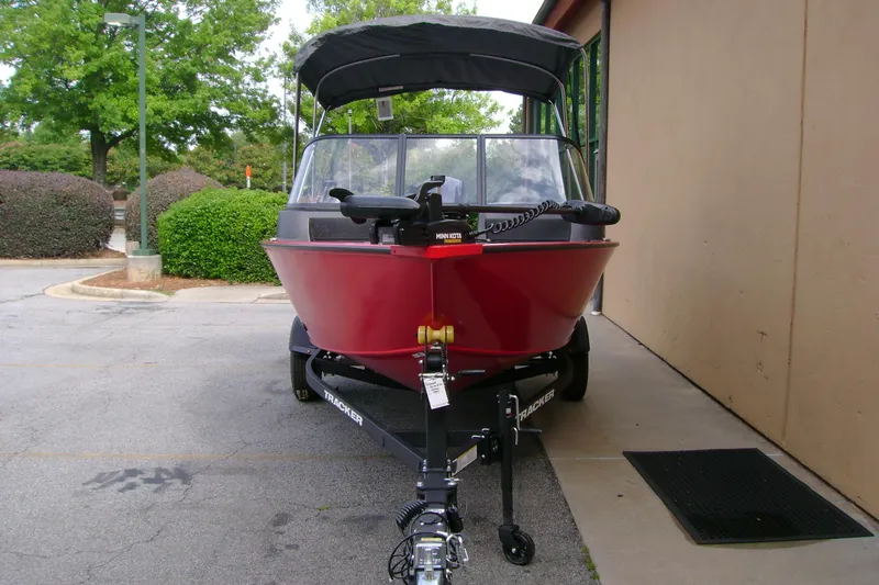 Slide: The Image of 2026 Tracker Pro Guide V-16 WT boat with red hull, parked outdoors. - 3