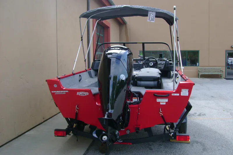 Slide: The Image of 2026 Tracker Pro Guide V-16 WT boat, red exterior, rear view with motor and canopy. - 4