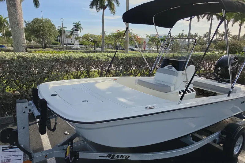 Slide: The Image of 2026 Mako Pro Skiff 13 CC boat on trailer, parked outdoors with palm trees. - 2