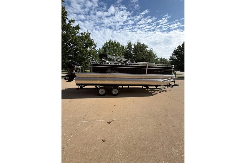 Slide: The Image of 2026 Sun Tracker Fishin' Barge 22 DLX pontoon boat on trailer, parked outdoors. - 98