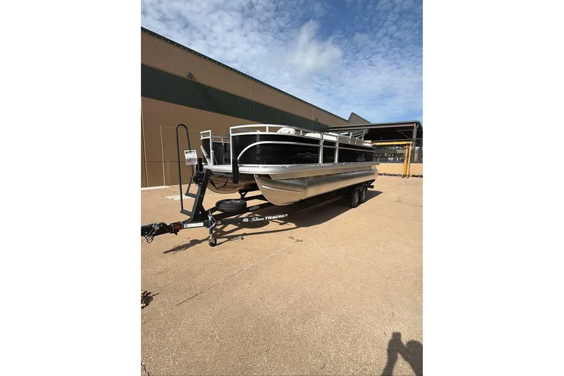 Slide: The Image of 2026 Sun Tracker Fishin' Barge 22 DLX pontoon boat on trailer, parked outdoors. - 94