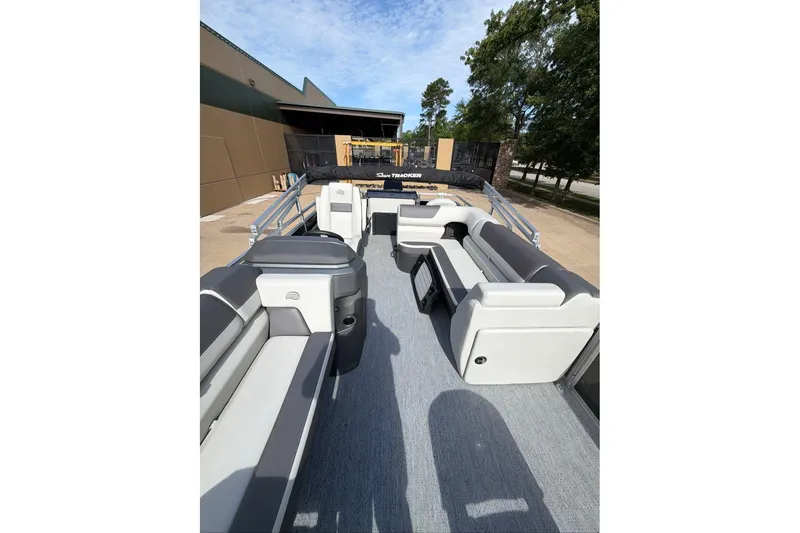 Slide: The Image of 2026 Sun Tracker Fishin' Barge 22 DLX interior with seating and helm, docked outdoors. - 95