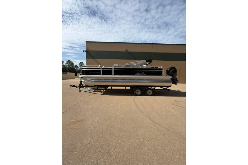 Slide: The Image of 2026 Sun Tracker Fishin' Barge 22 DLX pontoon boat on trailer, parked outdoors. - 92