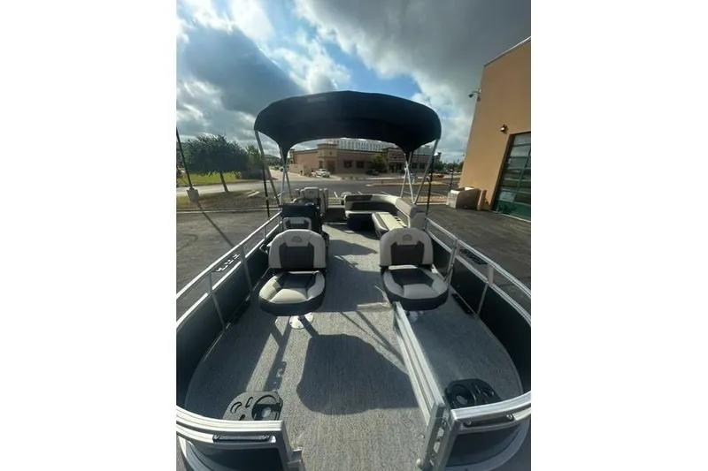 Slide: The Image of 2026 Sun Tracker Bass Buggy 16 XL Select pontoon boat with canopy, parked outdoors. - 4