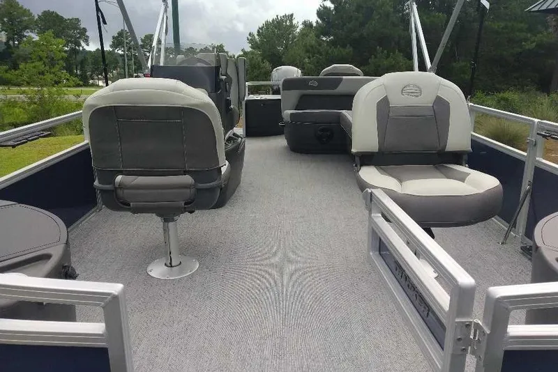 Slide: The Image of 2026 Sun Tracker Bass Buggy 18 DLX pontoon boat interior with gray seating and carpet. - 2
