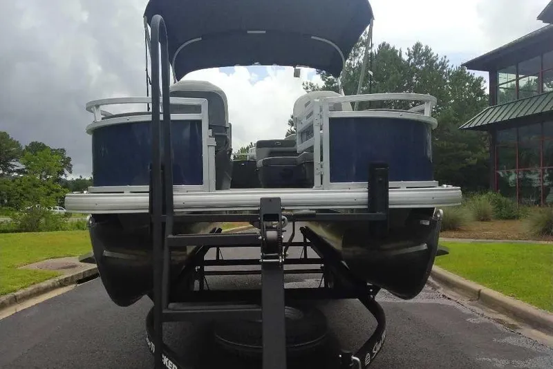 Slide: The Image of 2026 Sun Tracker Bass Buggy 18 DLX pontoon boat on trailer, parked outdoors. - 5