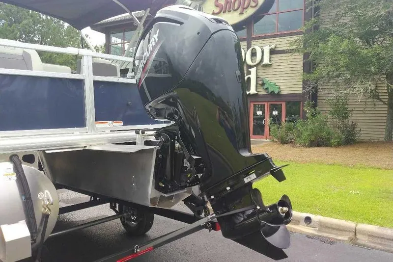 Slide: The Image of 2026 Sun Tracker Bass Buggy 18 DLX with Mercury outboard motor, parked outdoors. - 6