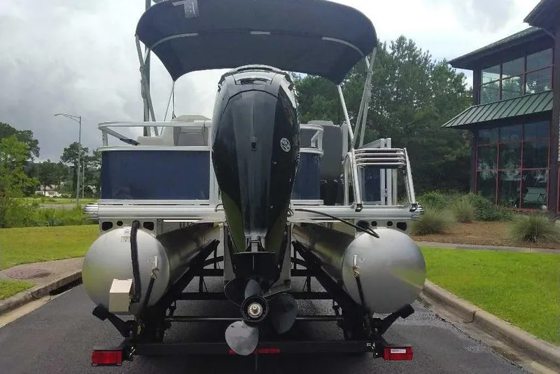 Slide: The Image of 2026 Sun Tracker Bass Buggy 18 DLX pontoon boat with outboard motor, parked outdoors. - 9