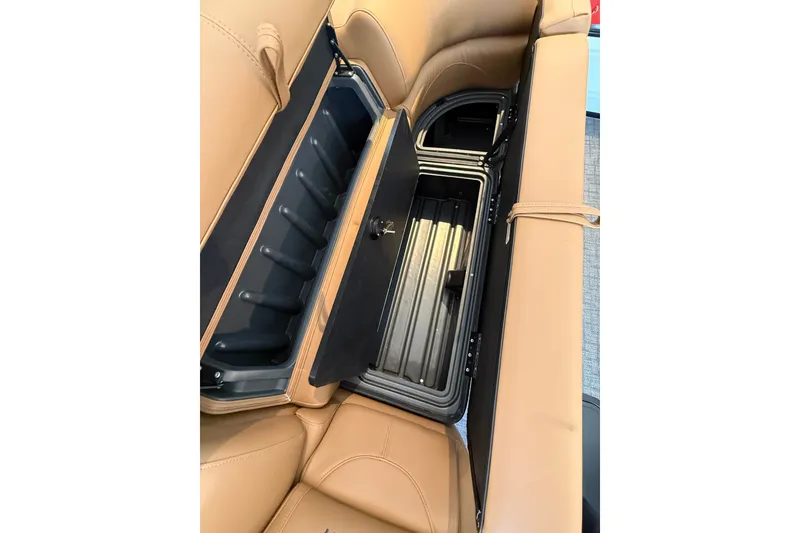 Slide: The Image of 2026 Regency 230 DL boat seat storage compartment with tan upholstery and integrated cooler. - 6