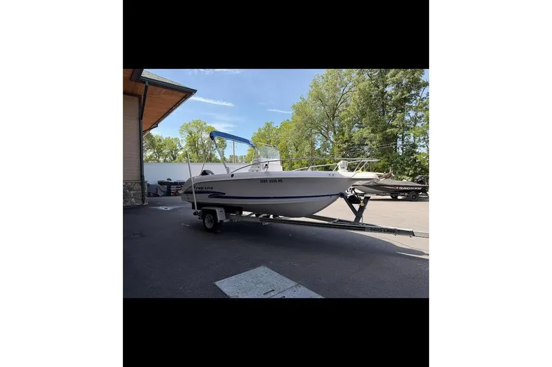 Slide: The Image of 2002 Pro-Line 19 Sport boat on trailer, parked outdoors near trees and building. - 3