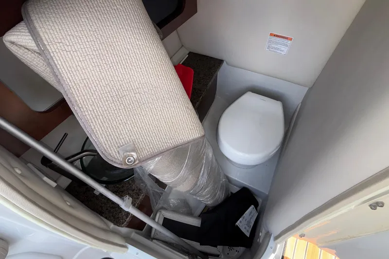 Slide: The Image of Interior of 2020 Crownline 290 SS boat showing compact bathroom with toilet and storage items. - 36