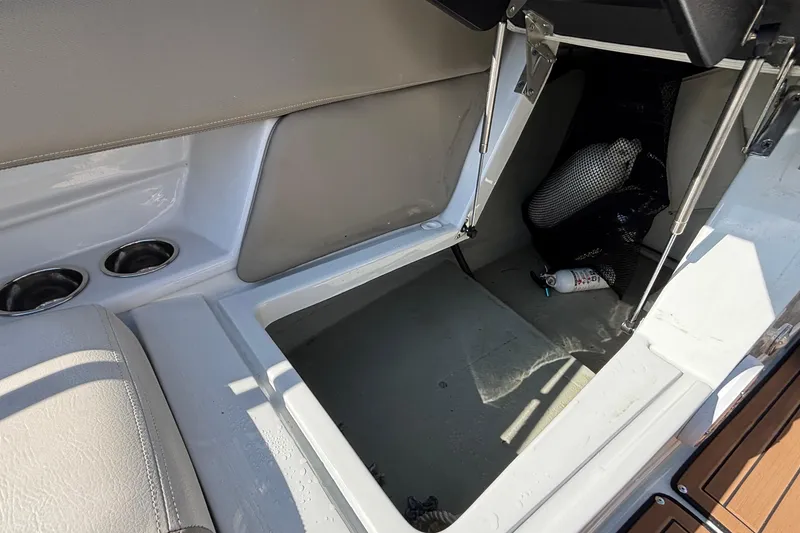 Slide: The Image of Open storage compartment in 2020 Crownline 290 SS boat, featuring cup holders and safety equipment. - 49
