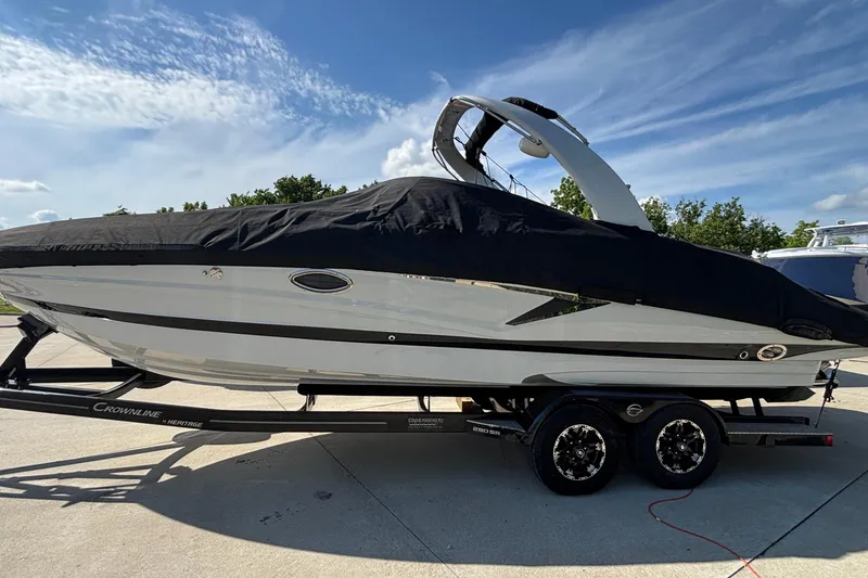 Slide: The Image of 2020 Crownline 290 SS boat on trailer, covered, under a clear blue sky. - 61