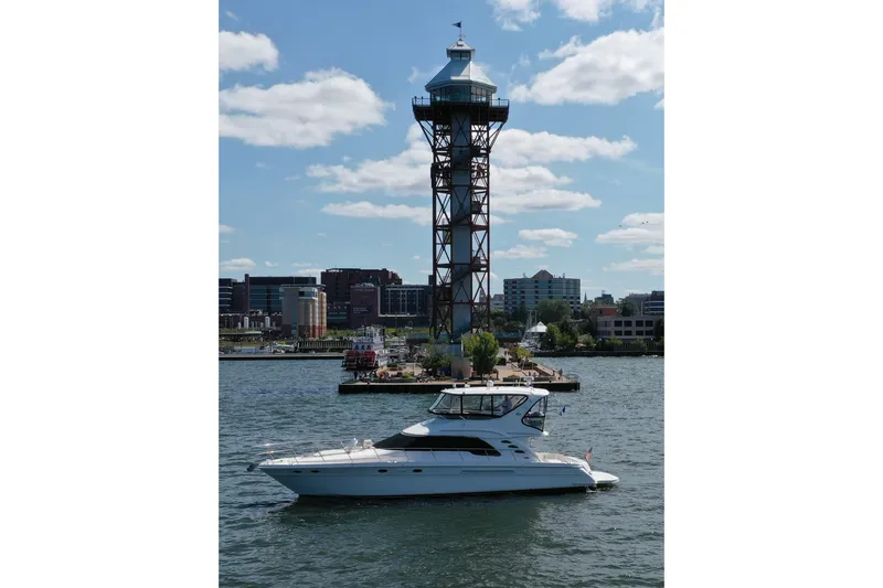Slide: The Image of 2002 Sea Ray 560 Sedan Bridge yacht on water near a tall observation tower. - 17