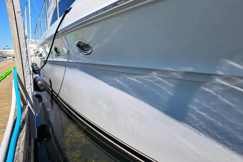 Slide: The Image of 2002 Sea Ray 560 Sedan Bridge yacht docked, reflecting sunlight on calm water. - 23