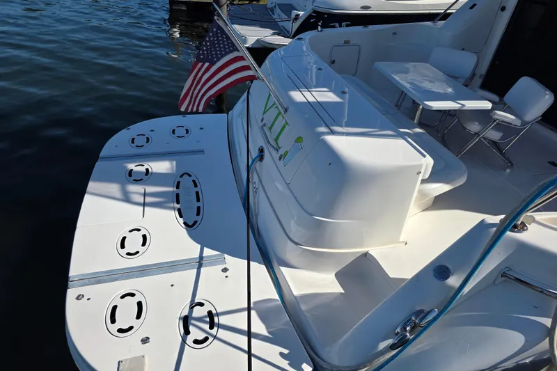Slide: The Image of 2002 Sea Ray 560 Sedan Bridge yacht with American flag, docked, featuring spacious deck area. - 25
