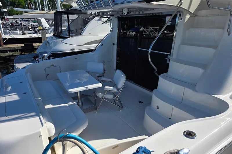 Slide: The Image of 2002 Sea Ray 560 Sedan Bridge yacht deck with seating and table, docked at marina. - 26