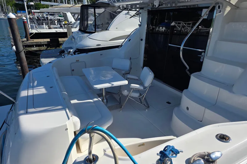 Slide: The Image of 2002 Sea Ray 560 Sedan Bridge yacht deck with seating and table, docked at marina. - 27