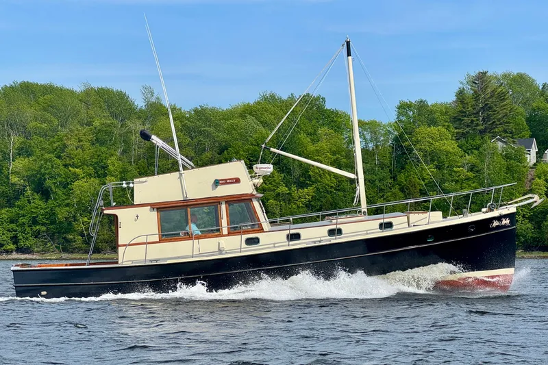Slide: The Image of 1976 Downeast Flybridge Cruiser sailing on a scenic river with lush green trees. - 1