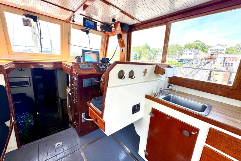 Slide: The Image of 1976 Downeast Flybridge Cruiser interior with helm, sink, and wooden cabinetry. - 10
