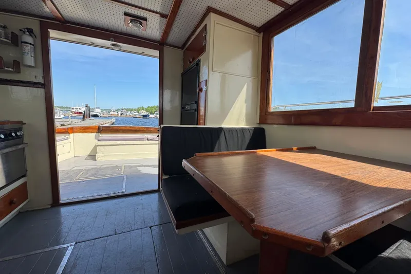 Slide: The Image of Interior of 1976 Downeast Flybridge Cruiser with dining area and view of marina. - 16