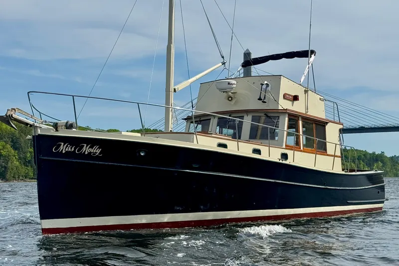 Slide: The Image of 1976 Downeast Flybridge Cruiser on water, named "Miss Molly," with scenic background. - 2