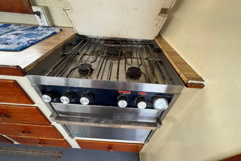 Slide: The Image of 1976 Downeast Flybridge Cruiser kitchen with a vintage gas stove and wooden cabinetry. - 24