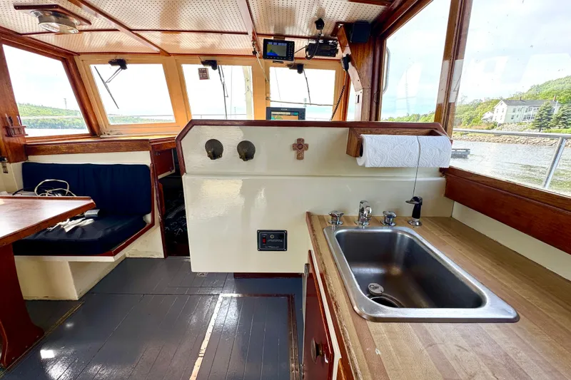 Slide: The Image of 1976 Downeast Flybridge Cruiser interior with sink, seating, and scenic window views. - 25