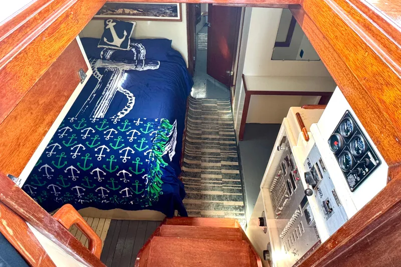 Slide: The Image of Interior of a 1976 Downeast Flybridge Cruiser with nautical-themed bedding and control panel. - 27