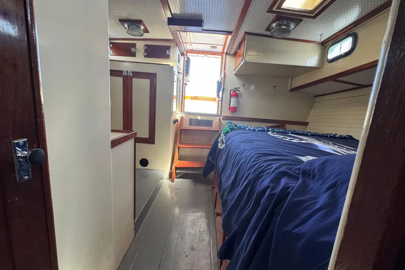 Slide: The Image of 1976 Downeast Flybridge Cruiser cabin interior with bed, stairs, and wooden accents. - 28