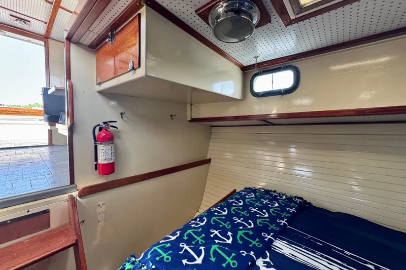 Slide: The Image of 1976 Downeast Flybridge Cruiser cabin with bed, fire extinguisher, and nautical-themed decor. - 32