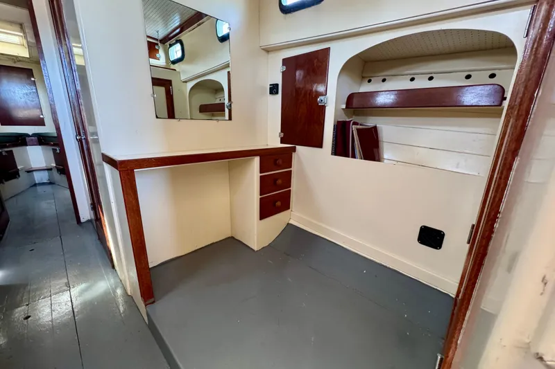 Slide: The Image of 1976 Downeast Flybridge Cruiser interior with wooden desk, mirror, and storage shelves. - 34
