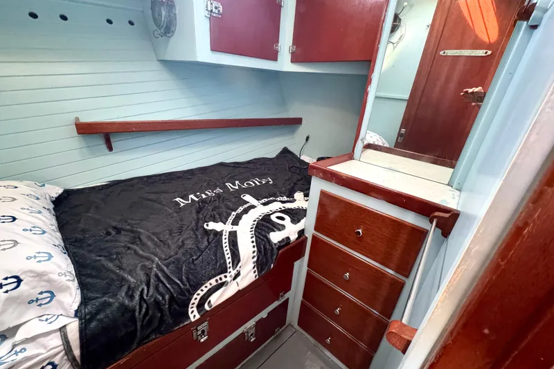 Slide: The Image of 1976 Downeast Flybridge Cruiser cabin interior with bed, wooden drawers, and nautical decor. - 39