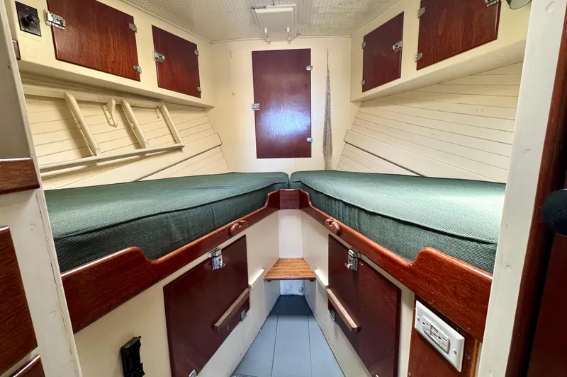 Slide: The Image of 1976 Downeast Flybridge Cruiser cabin with twin beds and wooden storage cabinets. - 43