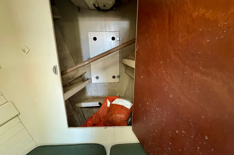 Slide: The Image of Interior view of a 1976 Downeast Flybridge Cruiser, showcasing storage space and wooden paneling. - 45