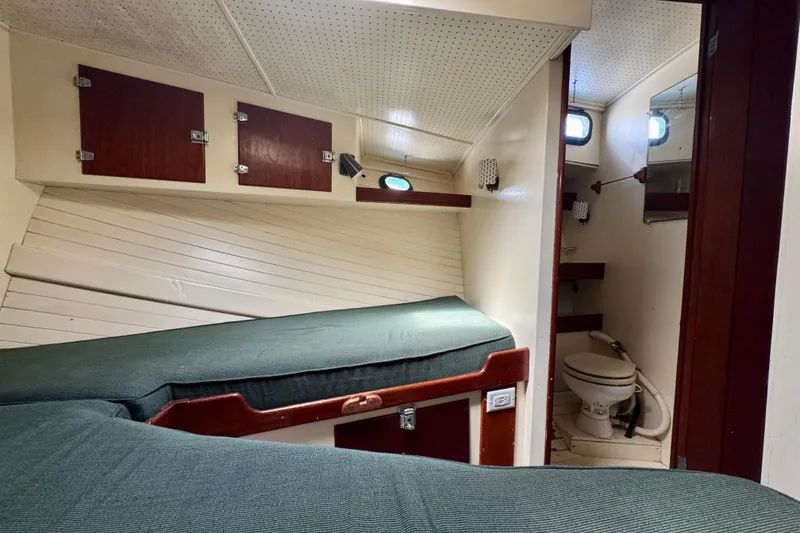 Slide: The Image of 1976 Downeast Flybridge Cruiser cabin interior with beds and compact bathroom. - 47