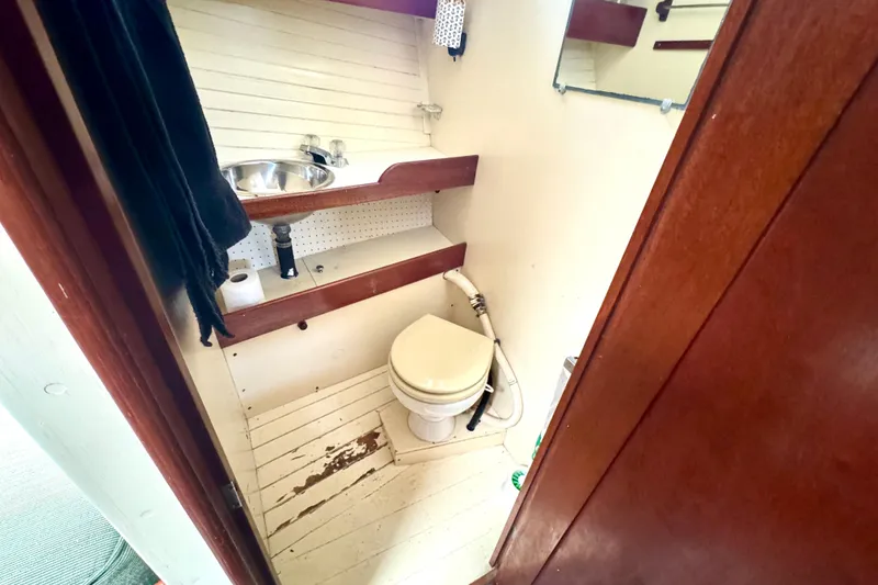 Slide: The Image of 1976 Downeast Flybridge Cruiser bathroom with sink, toilet, and wooden accents. - 48