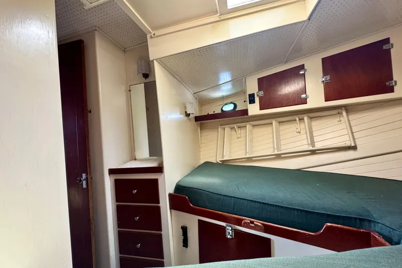 Slide: The Image of 1976 Downeast Flybridge Cruiser cabin interior with green bedding and wooden storage cabinets. - 49